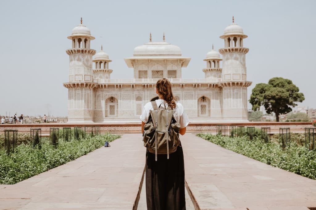 Foto da categoria "cultural": uma mulher de mochila nas costas contempla uma construção histórica.