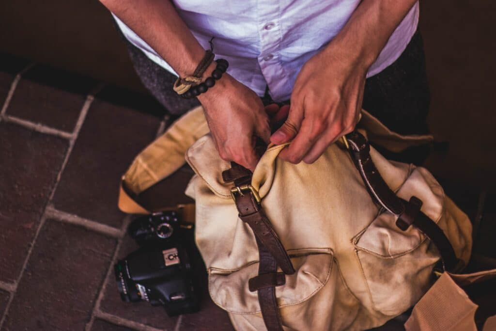 Imagem de um homem colocando um objeto dentro da mochila para um bate e volta.